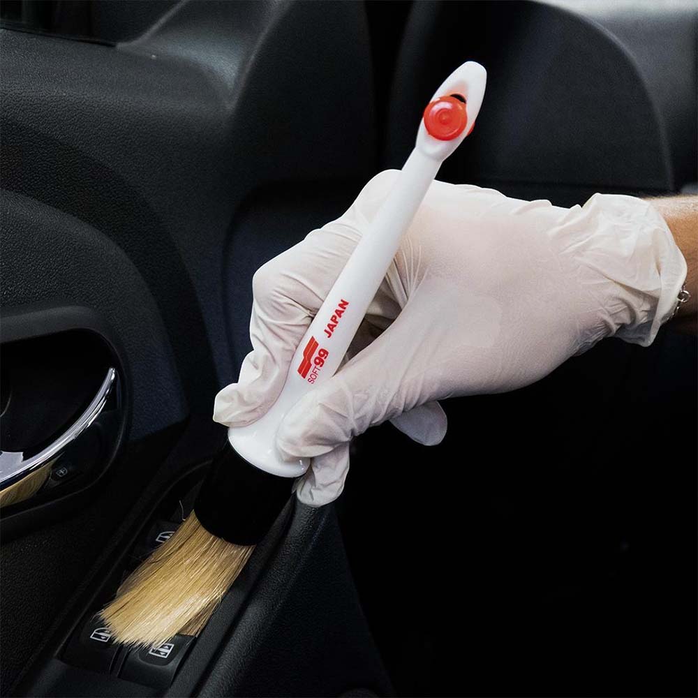 Detailer limpiando los recovecos del salpicadero del coche con la brocha Soft99